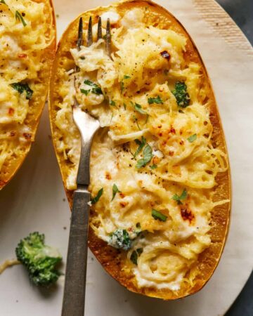A close up of spaghetti squash and broccoli alfredo with a fork.