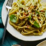 A close up of fettuccine with creamy avocado garlic sauce in a bowl with a fork.