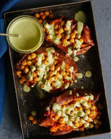 Roasted chickpea stuffed sweet potatoes with cilantro garlic cashew sauce on the side.