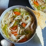 Bowls of chicken noodle soup with a spoon.