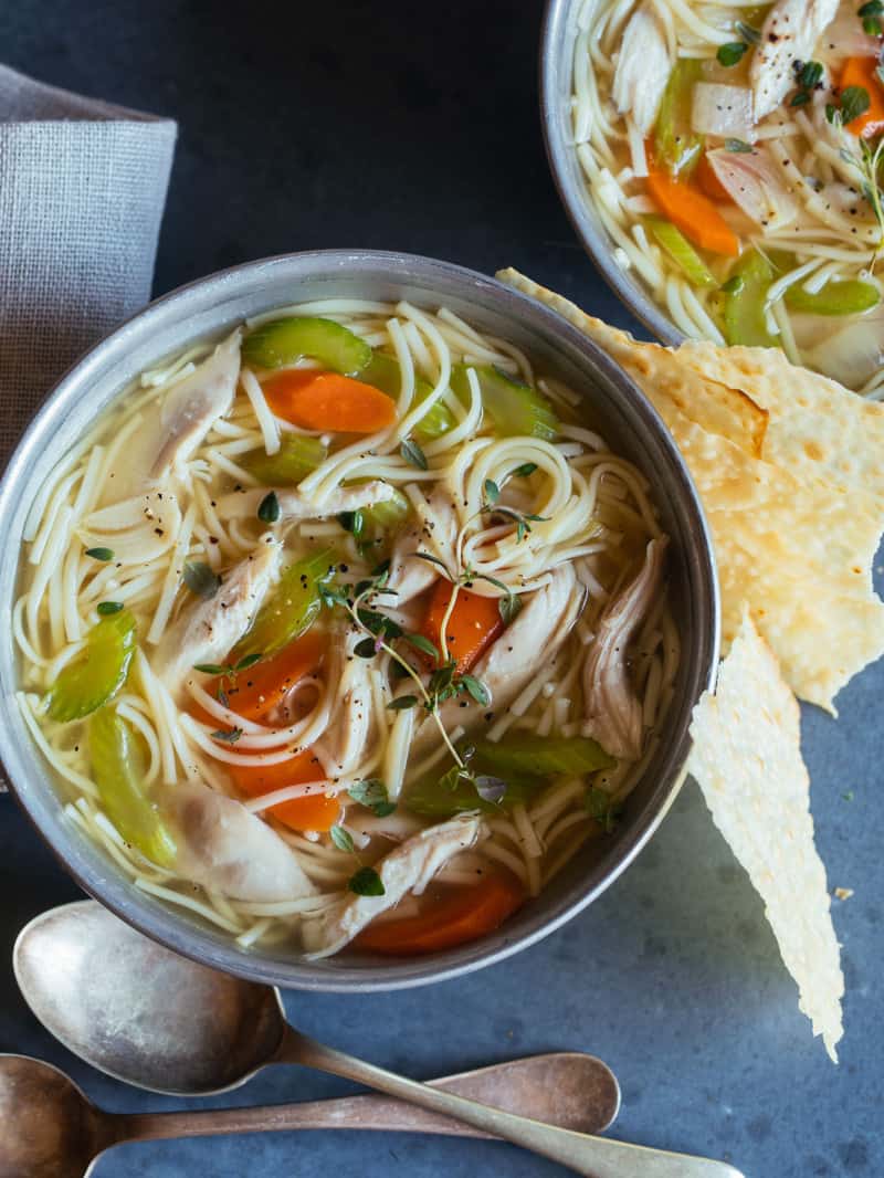 Bowls of chicken noodle soup with spoons.
