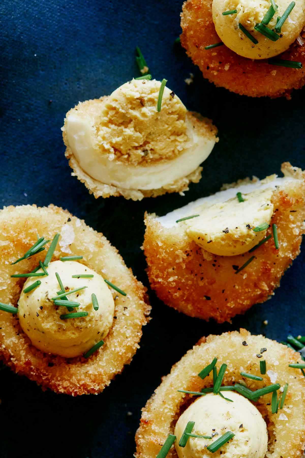 A close up of fried deviled eggs with one cut in half.
