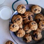 A plate of chai, chocolate chip, coconut, cookies and milk.