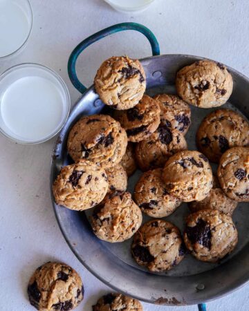 A plate of chai, chocolate chip, coconut, cookies and milk.