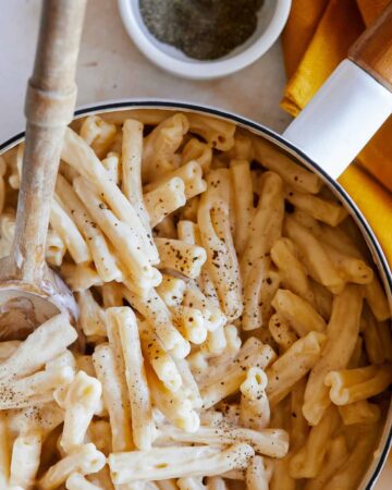 A close up of vegan stovetop mac and cheese with a wooden spoon.