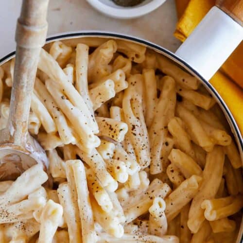 A close up of vegan stovetop mac and cheese with a wooden spoon.