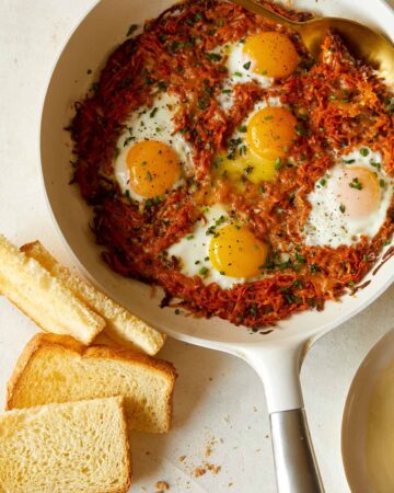 Cheesy skillet sweet potato hash browns and eggs with toast.