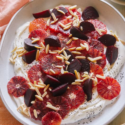 Blood orange and beet salad over honeyed yogurt in a bowl.