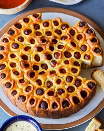 Pull apart pigs in a blanket with some pulled out on a plate.