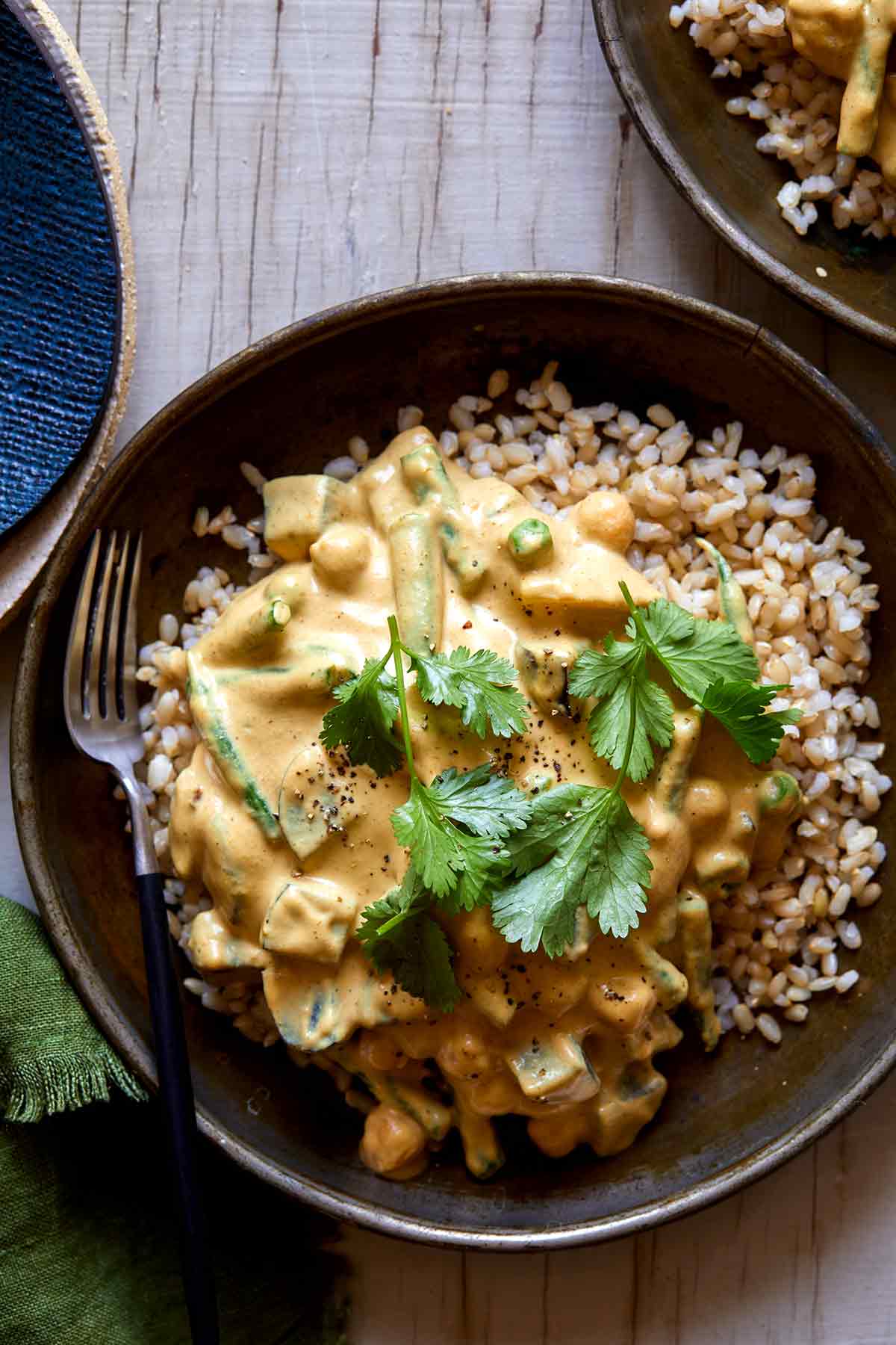 Vegetable loaded vegan korma in a bowl with a fork.