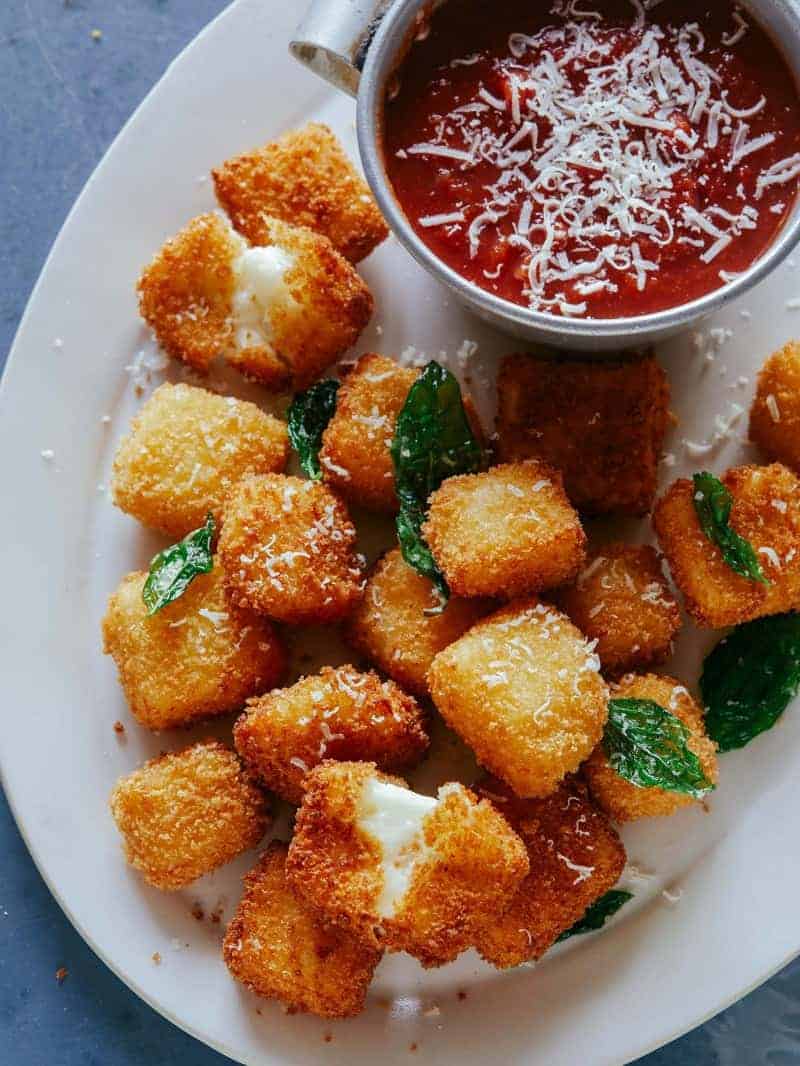 A close up of halloumi nuggets with marinara sauce on the side, a Super Bowl snack. 