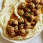 A close up of Swedish meatballs over mashed potatoes.