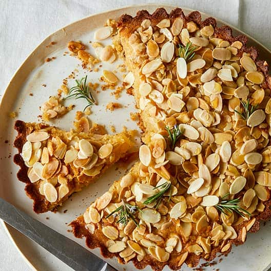 Almond honey cornmeal cake, sliced with slices removed and a knife.