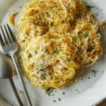 Garlic and herb capellini with a fork and spoon on a plate.