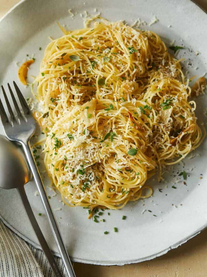 Garlic and herb capellini with a fork and spoon on a plate.