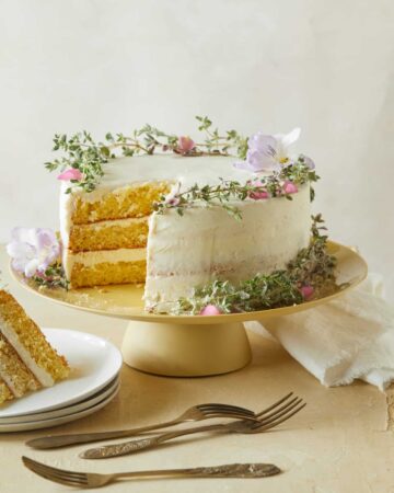 A browned butter cake with vanilla honey frosting with a slice on a plate and forks.