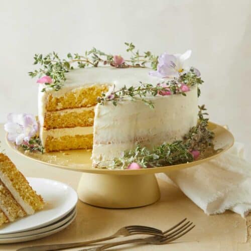 A browned butter cake with vanilla honey frosting with a slice on a plate and forks.