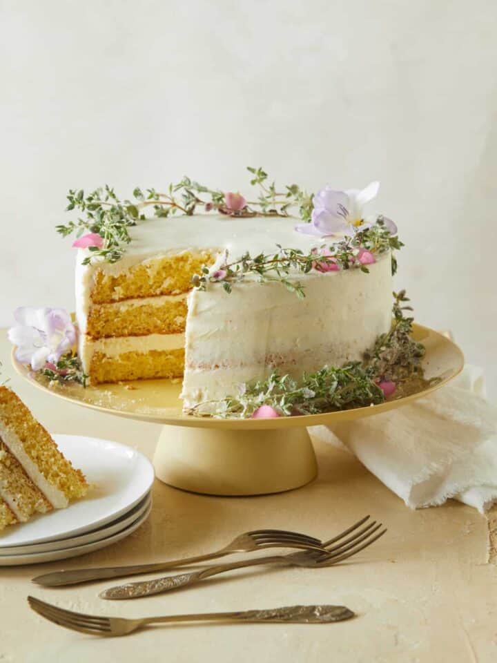 A browned butter cake with vanilla honey frosting with a slice on a plate and forks.