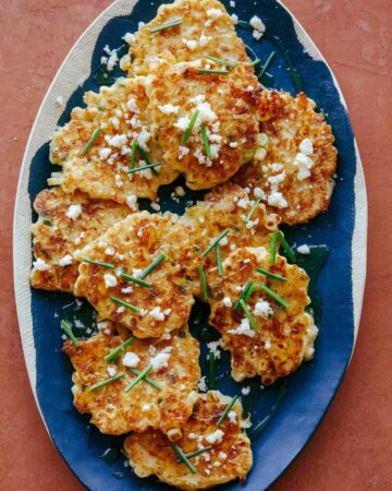 Corn cakes with chives and queso fresco on blue and white platter.