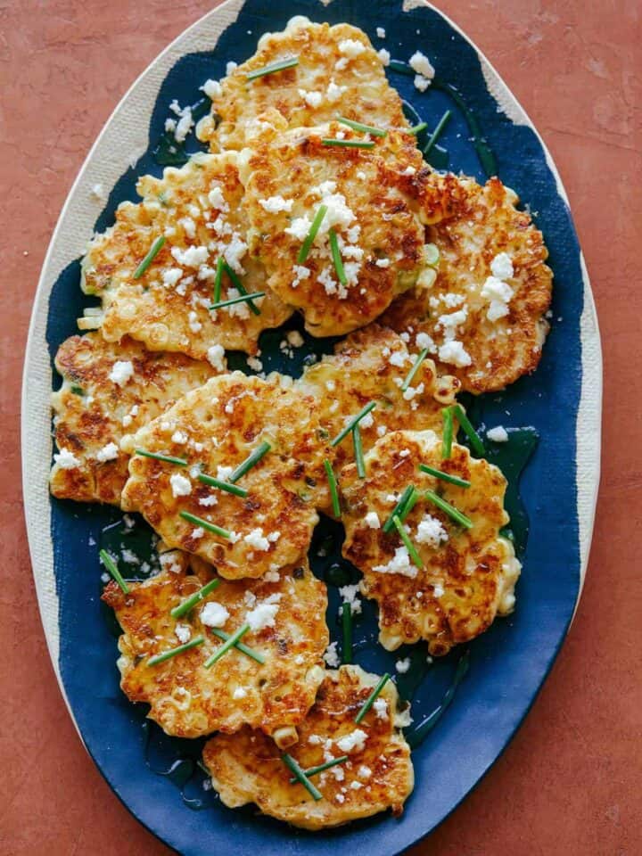 Corn cakes with chives and queso fresco on blue and white platter.