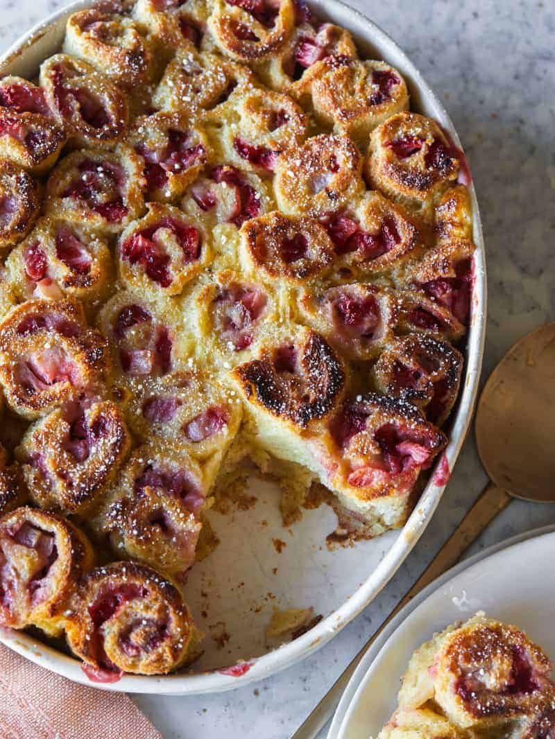 Strawberry French Toast Roll ups in an oval baking dish with some scooped out. 