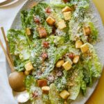 Simple salad with quince, manchego, and marcona almonds with serving spoons.