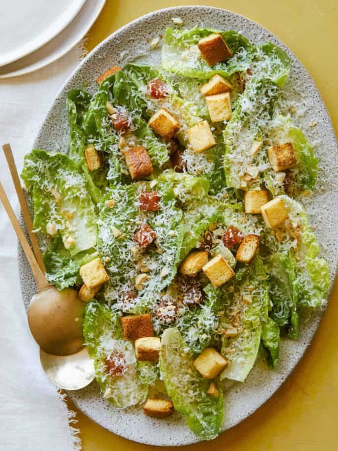 Simple salad with quince, manchego, and marcona almonds with serving spoons.