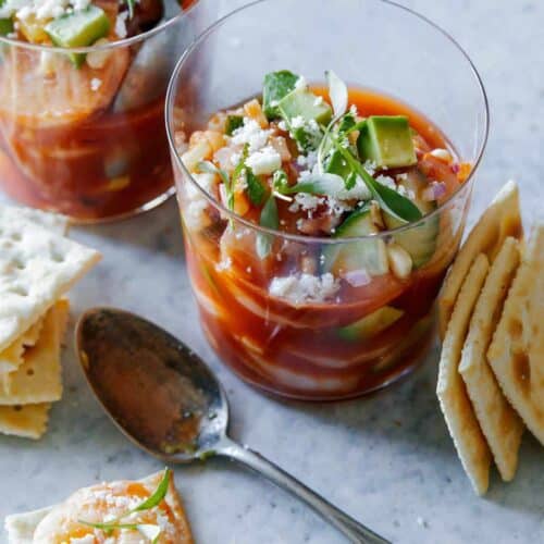 Glasses of Mexican shrimp cocktails with saltine crackers and spoons.