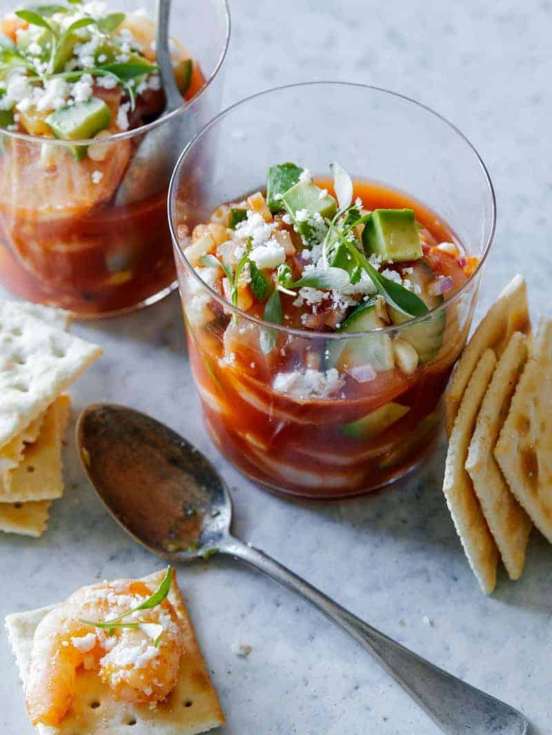 Glasses of Mexican shrimp cocktail with crackers and spoons.