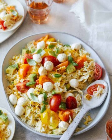 A plate of loaded pasta salad with a spoon.