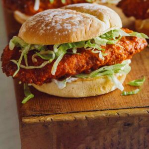 A close up of Nashville honey hot chicken sandwiches on a wooden cutting board.