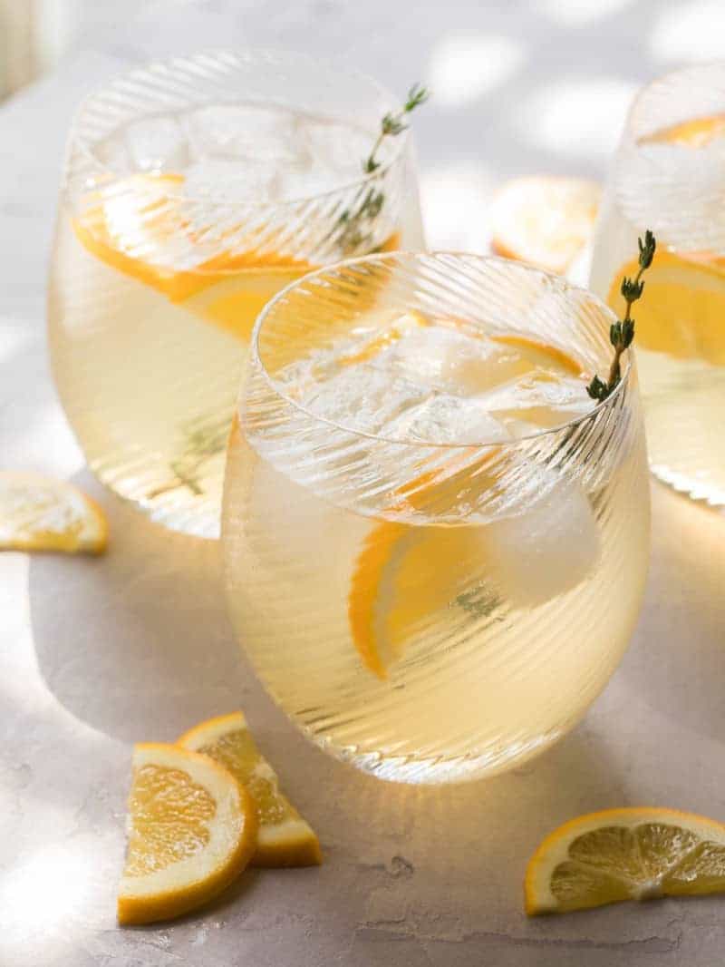 Bees Knees cocktail with lemon wedges and thyme. 