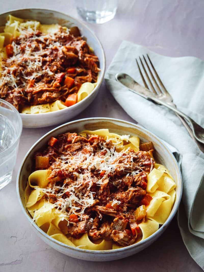 Pork Ragu on top of a bed of pappardelle noodles in two bowls.