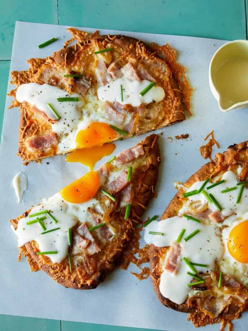 Croque madame flatbreads cut in half with mornay sauce.