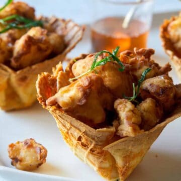 A close up of popcorn chicken in cheesy waffle cups.