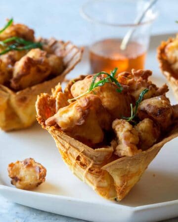 A close up of popcorn chicken in cheesy waffle cups.