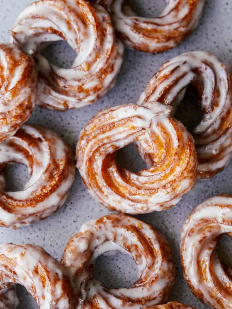 A close up of vanilla glazed pumpkin crullers.