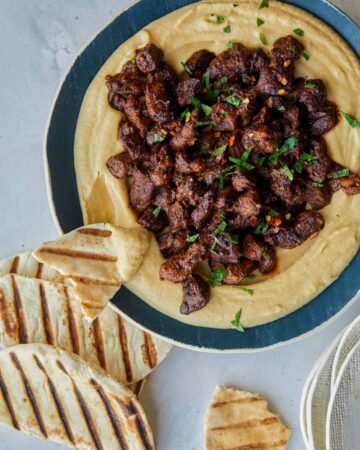 Spiced lamb over roasted garlic hummus with pita on the side.