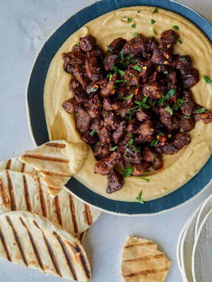 Spiced lamb over roasted garlic hummus with pita on the side.