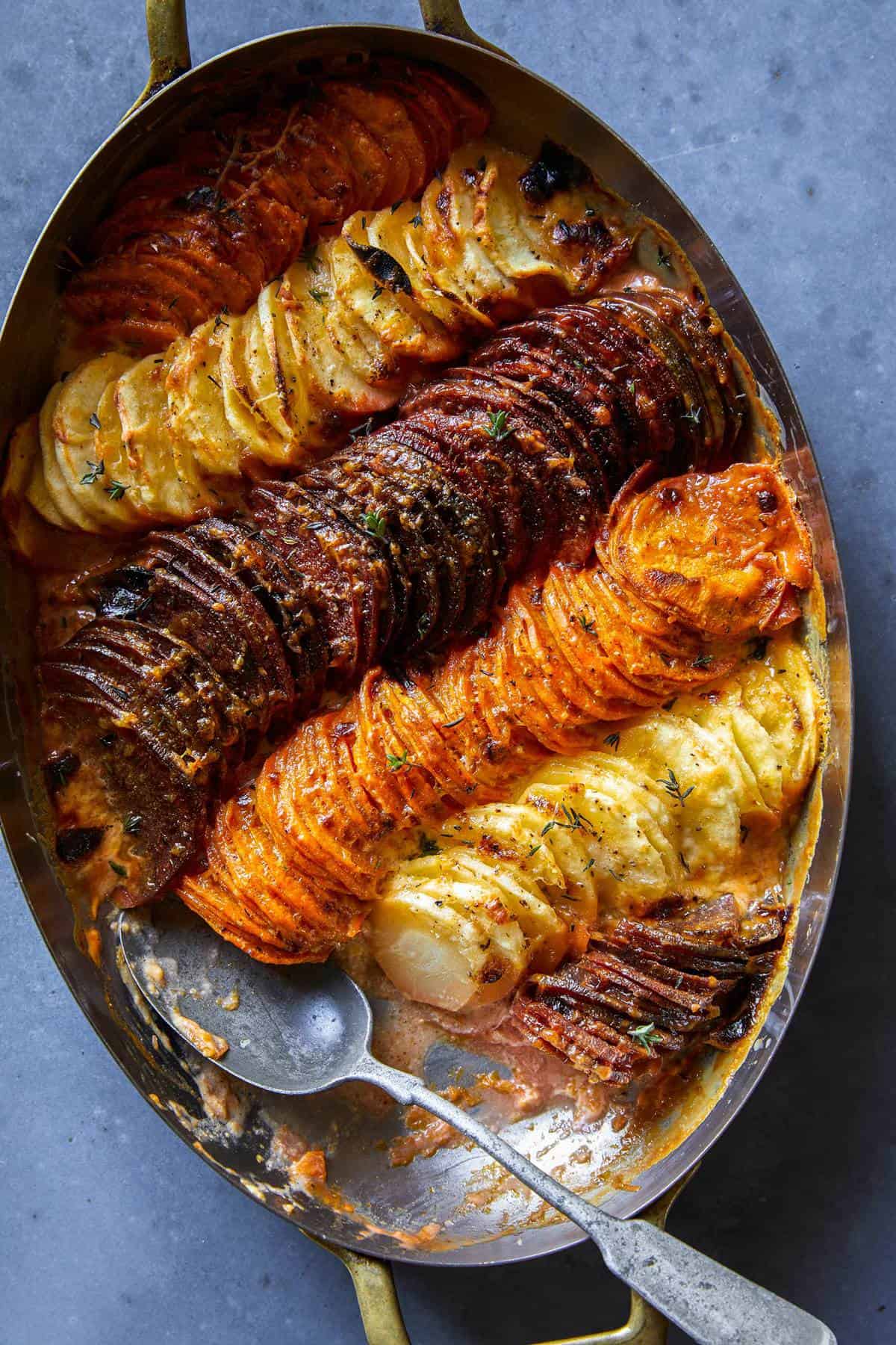 A close up of cheesy root vegetable gratin with a spoon.