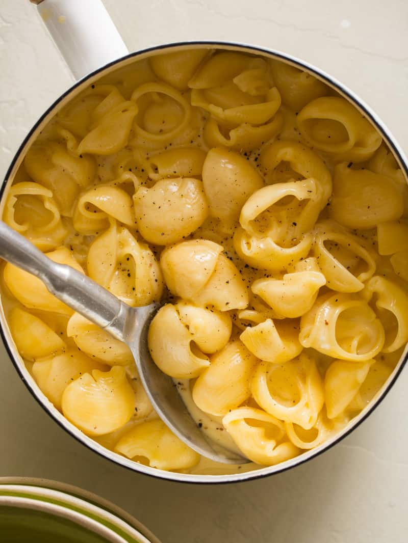 A close up of a bowl of classic creamy stovetop mac and cheese with a spoon.