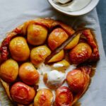 Sliced honey crisp apple tart tatin with melting whipped cream.