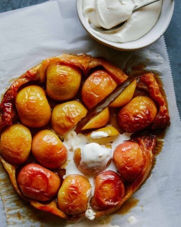 Sliced honey crisp apple tart tatin with melting whipped cream.