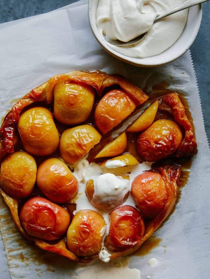 Sliced honey crisp apple tart tatin with melting whipped cream.