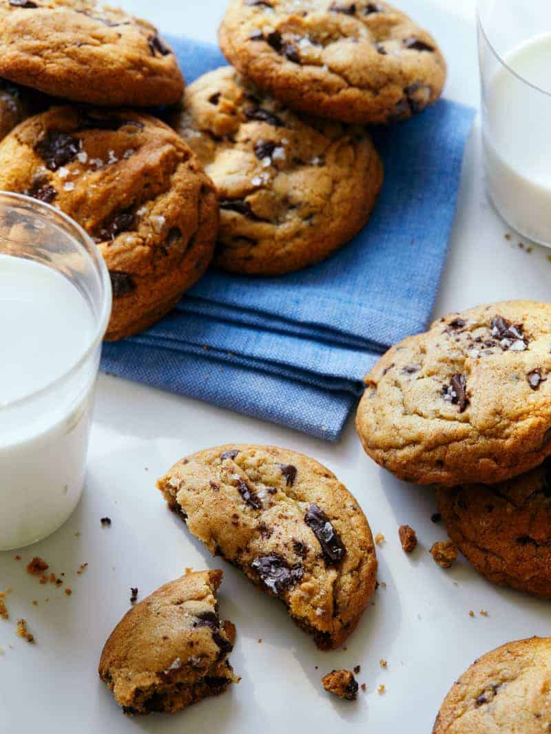 A close up of salted brown butter chocolate chip cookies with napkins and milk.