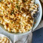 Taleggio mac and cheese topped with buttery crackers with a spoon.