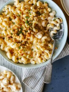 Taleggio mac and cheese topped with buttery crackers with a spoon.