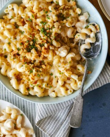 Taleggio mac and cheese topped with buttery crackers with a spoon.