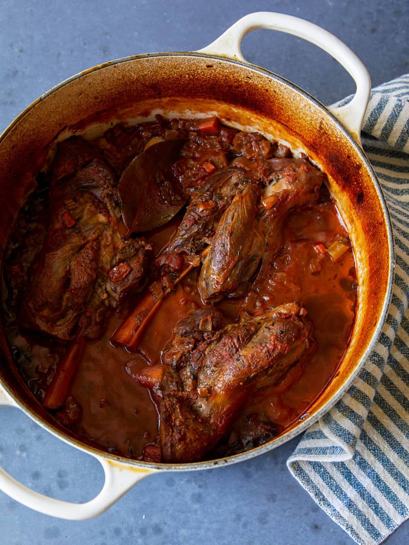 Braised lamb shanks in a large pot.