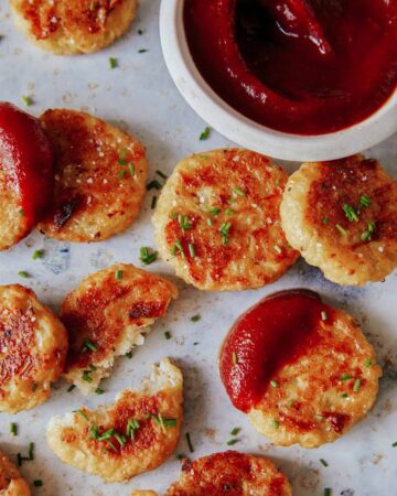 A close up of crispy baked cauliflower tots with sauce.